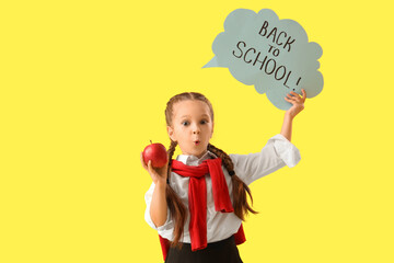 Shocked little girl holding speech bubble with text BACK TO SCHOOL and apple on yellow background