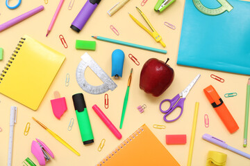 School supplies with scissors, protractor and red apple on beige background. Top view