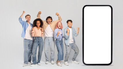 A diverse group of young adults, including a Black woman, Asian man, and Caucasian men and women, are standing in front of a large smartphone and celebrating their success with raised fists