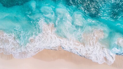 A mesmerizing aerial view of turquoise waves creating white foam as they crash onto a sandy shoreline, perfectly capturing the beauty and power of the ocean's edge.