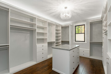 Luxurious Walk-In Closet With White Shelves And Elegant Chandelier