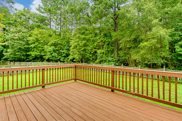 Sunny Wooden Deck With Railing Overlooking Lush Green Backyard