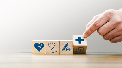 Health insurance concept, Hand Arranging Wooden Blocks with Medical Icons Including Heartbeat, Stethoscope, Syringe, and Healthcare Cross Symbol, Future Healthcare Technology