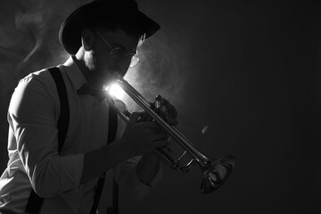 Fototapeta premium Professional musician playing trumpet on dark background with smoke, space for text. Black and white effect