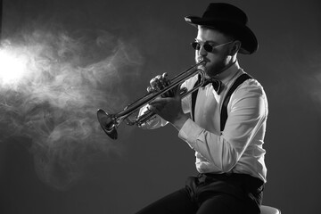 Professional musician playing trumpet on dark background with smoke, space for text. Black and white effect