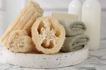 Loofah sponges, towels and soap on white marble table