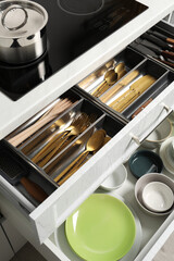 Ceramic dishware and cutlery in drawers indoors