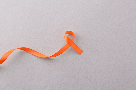 Orange awareness ribbon on gray background, top view. Space for text