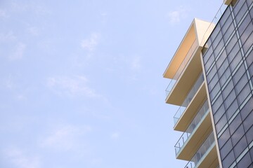 Modern building with big windows against blue sky outdoors, low angle view. Space for text