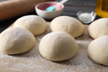 Raw dough balls and flour on table, closeup