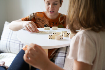 Closeup shot cute little girl playing dominos with her mother 