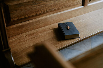 High angle view no people shot of Bible book with cross on wooden pew in Catholic church