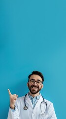 Portrait of a Happy Doctor Pointing at Empty Space on Blue Background. Friendly Young Male Doctor Introducing Medical Products, Clinic Events, Vaccine Promotion, Health Flyers, and Healthy Lifestyle 