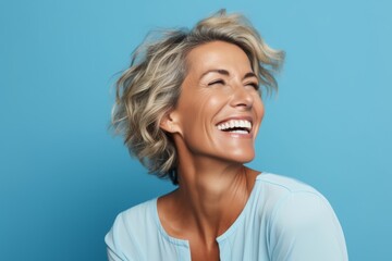 Beautiful smiling middle aged woman with blond hair on blue background.