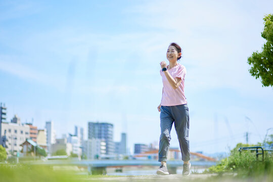 春の新緑の中ランニングを楽しむスポーツウェアをきたシニア女性