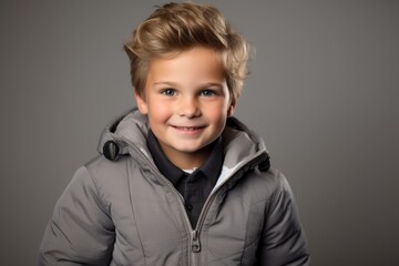 Portrait of a smiling little boy in a warm jacket. Studio shot.