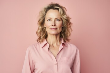Portrait of beautiful middle aged woman in pink shirt on pink background