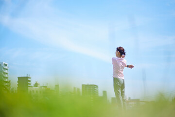 春の新緑の中ストレッチをを行うスポーツウェアをきたシニア女性