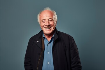 Fototapeta premium Portrait of a happy senior man smiling at the camera against blue background