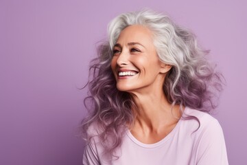 Portrait of smiling senior woman with long wavy hair on purple background