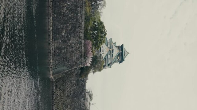 Vertical - Tilt-down Revealing Shot Of Famous Osaka Temple And Its Moat In Osaka, Japan.