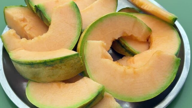 Putting a plate full of sliced musk melon on the table