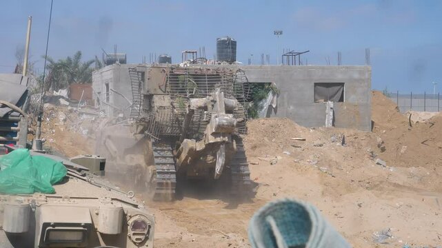 IDF Caterpillar D9 armored bulldozers moving slowly on destroyed city streets during Israel Hamas war