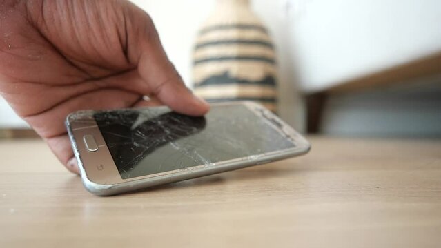 hand pick a broken smart phone from a floor