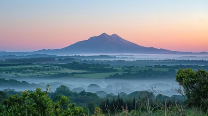 Obraz premium A mountain range is visible in the distance with a foggy mist surrounding it
