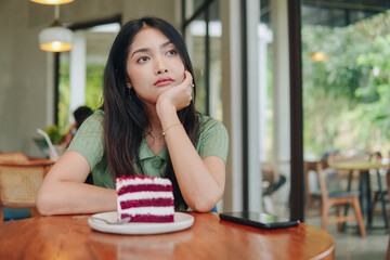 A woman sits at a table with a slice of cake in front of her.