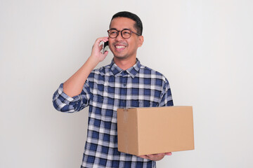 A man holding order package while answering a phone call from his customer. Online business concept