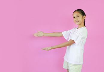 Portrait of Asian girl child standing presenting something on copy space isolated on pink studio background. Image with clipping path.