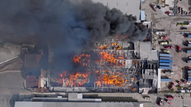 Top down aerial view of blazing fire and black smoke at burning factory