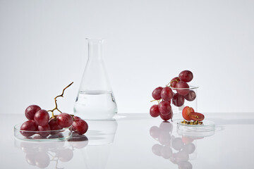 Natural grape seed oil contained in an erlenmeyer flask, which placed on white table, next to some...