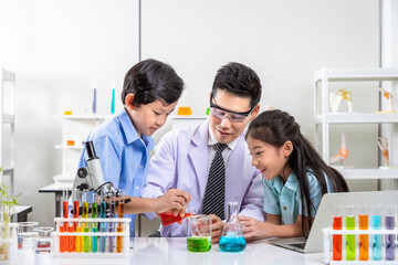 Asian teacher and young students engaged in chemistry experiments in school science lab