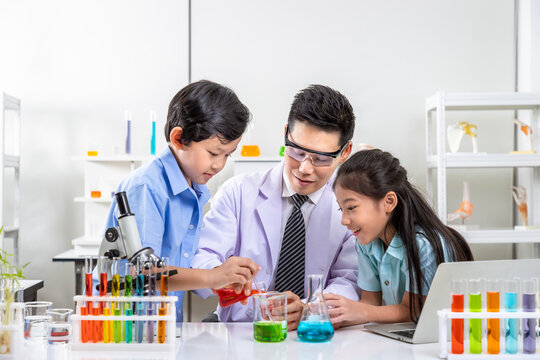 Asian teacher and young students engaged in chemistry experiments in school science lab