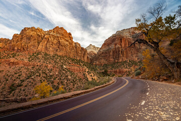 Zion National Park in Utah is known for offering a stunning drive with vibrant red rock formations, complemented by fall foliage and a striking sky, ideal for nature enthusiasts and outdoor lovers