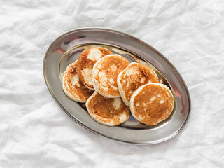 Greek yogurt pancakes on a metal plate on a light background, top view