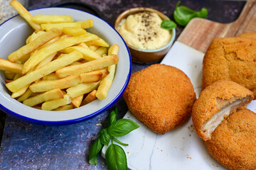  Crispy  deep fried home made     chicken Cordon bleu with cheese   and ham  and french fries on wooden rustic background.  