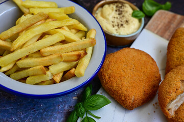  Crispy  deep fried home made     chicken Cordon bleu with cheese   and ham  and french fries on wooden rustic background.  