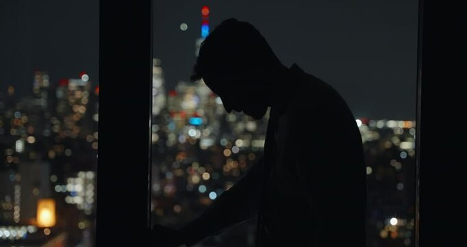 Businessman devastated and upset. standing in windows at night stressed and down urban background. Lose money stock market, depressed. guy in suit by panoramic view of skyscrapers, commit suicide. 