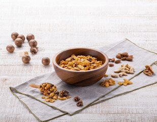 나무 그릇에 시리얼과 여러가지 견과류를가 있다.