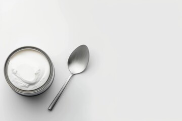 Minimalist yogurt cup and spoon on white background