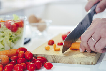 Chef at home using a knife cutting fresh raw vegetables. Cooker at home making a healthy vegetable meal, cutting up veggies - food and drink 4k footage - One man preparing salads in the kitchen