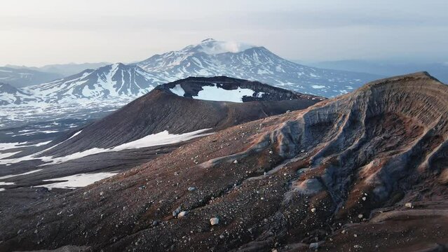 View of Mutnovsky volcano from the crater of Gorely volcano. Kamchatka peninsula, Russia. Aerial drone view. Beautiful landscape at sunrise.
