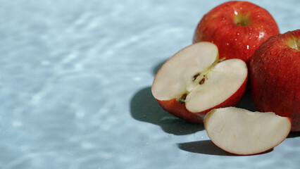 Close up of red apples with a slice on blue wet background. Macro of sliced apple with apple place...