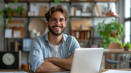 Naklejka premium A man with glasses smiling confidently while working on a laptop in a modern, cozy office setting, exuding professionalism and approachability.