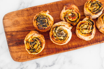 pumpkin spinach and cheese pastry rolls on wooden cutting board, freshly baekd and homemade,