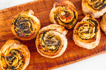 pumpkin spinach and cheese pastry rolls on wooden cutting board, freshly baekd and homemade,