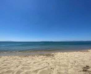 The beach of luxury hotel. Sunny day, calm waveless sea, blue sky. Soft yellow-gold brown-gold sand shines on beach. sea ​​waves hitting the seashore. clear and clean sea water. Balıkesir in Turkiye